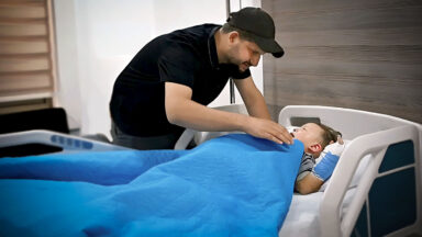 A concerned father calms his 3 year old son before undergoing surgery.